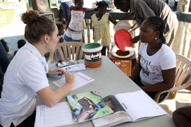 Cap Haitien, Haiti - January 14, 2015: A SOIL employee talks with a woman about getting an EkoLakay Ecosan home composting toilet at a park in the Shada neighborhood.  SOIL provides and services the toilets, which provide the basic elements, human waste and shredded vegetable matter, of compost that will, once completed and tested for pathogens, be used to grow fruits and vegetables, for approximately four dollars a month.